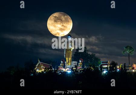 Chiang mai, Thaïlande. 17 octobre 2024. La pleine lune, vue sur l'une de ses orbites les plus proches de la Terre, flotte près de la statue debout de Bouddha à Wat Phra That Doi Kham. La pleine lune orbite le plus près de la Terre, connue sous le nom de « Supermoon », faisant paraître la lune plus grande et plus lumineuse que d'habitude. Crédit : SOPA images Limited/Alamy Live News Banque D'Images