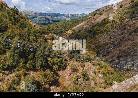 Sasso di Castalda, Italie - août 2024 : une vue aérienne capture une longue passerelle suspendue s'étendant sur un terrain rocheux avec un vert environnant A. Banque D'Images