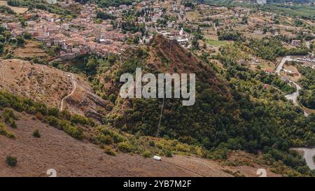 Sasso di Castalda, Italie - août 2024 : une vue aérienne capture une longue passerelle suspendue s'étendant sur un terrain rocheux avec un vert environnant A. Banque D'Images