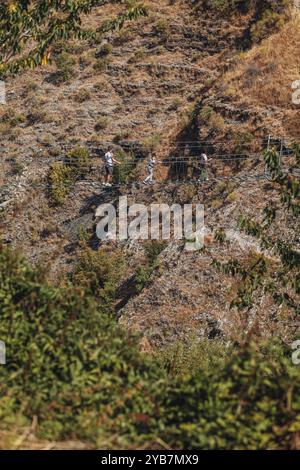 Sasso di Castalda, Italie - août 2024 : une vue aérienne capture une longue passerelle suspendue s'étendant sur un terrain rocheux avec un vert environnant A. Banque D'Images