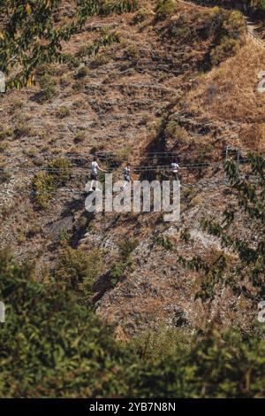 Sasso di Castalda, Italie - août 2024 : une vue aérienne capture une longue passerelle suspendue s'étendant sur un terrain rocheux avec un vert environnant A. Banque D'Images
