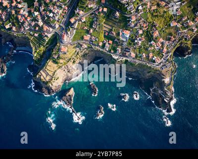 Vue aérienne de Coastal Village surplombant Rocky Shoreline et Turquoise Waters Banque D'Images