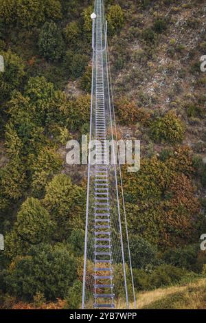 Sasso di Castalda, Italie - août 2024 : une vue aérienne capture une longue passerelle suspendue s'étendant sur un terrain rocheux avec un vert environnant A. Banque D'Images