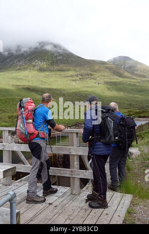 Hommes debout sur un pont en bois près du Loch Eilde Mor regardant le Munros Sgor Eilde Beag & Sgurr Eilde Mor près de Kinlochleven dans les Highlands écossais. Banque D'Images