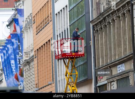 Munich, Allemagne. 15 octobre 2024. Un homme sur une plate-forme élévatrice travaille sur la façade dans la zone piétonne de la capitale bavaroise. Crédit : Peter Kneffel/dpa - ATTENTION : utiliser uniquement en format complet/dpa/Alamy Live News Banque D'Images