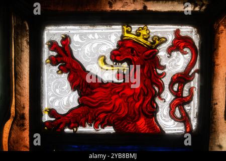 Détail d'un vitrail. Un symbole de style médiéval d'un lion rouge féroce et agressif levant ses griffes. Il porte une couronne d'or sur la sienne Banque D'Images