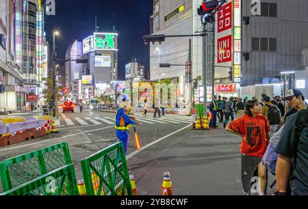 Ouvrier japonais en uniforme dirigeant la circulation autour des travaux routiers la nuit à Shinjuku, Tokyo, Japon, le 23 septembre 2023 Banque D'Images
