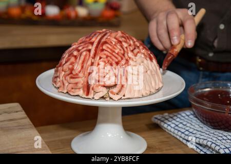 Un gâteau en forme de cerveau avec fraise source brossée sur elle pour faire l'aspect de gâteau éponge comme un vrai cerveau humain sanglant pour la partie halloween Banque D'Images
