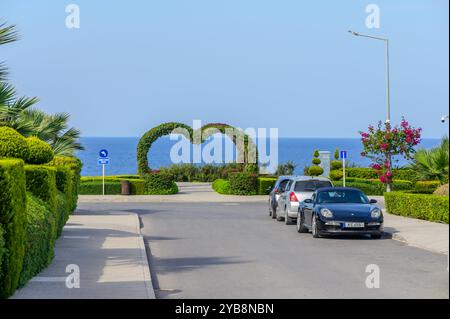 Une route côtière pittoresque mène à une magnifique arche en forme de cœur faite de verdure luxuriante, invitant les couples à profiter d'une promenade romantique le long de la belle Banque D'Images