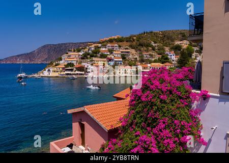Vue aérienne d'Assos, Céphalonie. Village pittoresque niché sur une péninsule, entouré d'eaux turquoises. Maisons colorées, petite plage et bateaux i Banque D'Images
