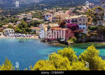 Un village pittoresque à Assos, Céphalonie, Grèce. Des maisons colorées bordent la côte avec un petit port et des bateaux. L'image est encadrée par un b rose vif Banque D'Images