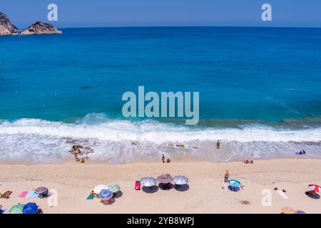 Entouré de falaises, la plage Petani Beach de Céphalonie présente des eaux turquoises, du sable doré. Il est idéal pour nager et se détendre, avec des chaises longues et Banque D'Images