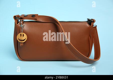 Sac avec porte-clés en bois en forme de visage souriant sur fond bleu clair Banque D'Images