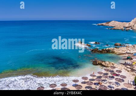 Entouré de falaises, la plage Petani Beach de Céphalonie présente des eaux turquoises, du sable doré. Il est idéal pour nager et se détendre, avec des chaises longues et Banque D'Images