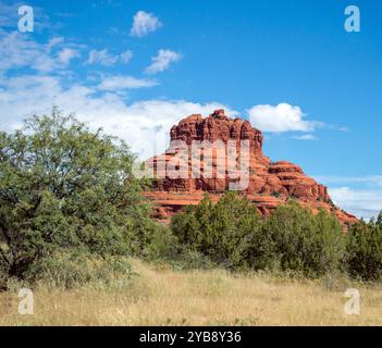 Le magnifique Red Bell Rock à Sedona, Arizona contre un beau ciel bleu vif avec des nuages blancs en arrière-plan et une végétation verte à l'avant Banque D'Images
