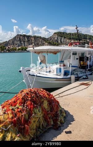 Bateau de pêche grec traditionnel dans le port de la ville de Zante ou de la ville de Zakynthos en Grèce avec des filets de pêche méditerranéens colorés au premier plan. Banque D'Images