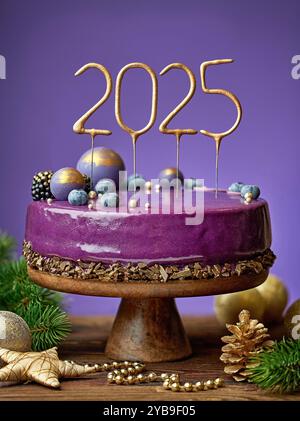 Beau gâteau décoré violet sur table en bois et fond violet. Sparklers numéros 2025 Banque D'Images