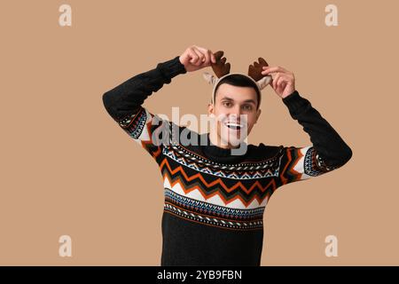 Heureux jeune homme dans des cornes de renne sur fond beige Banque D'Images