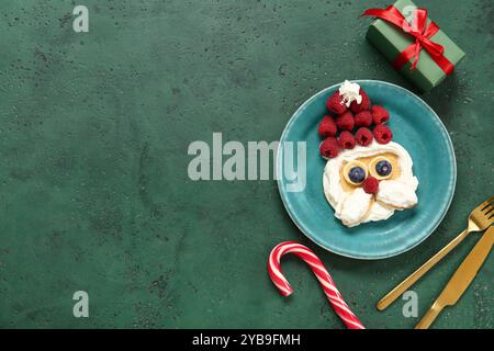 Assiette avec crêpe en forme de Père Noël sur la table verte. Fête de Noël Banque D'Images