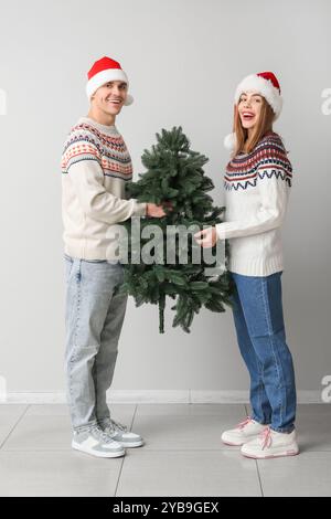 Heureux jeune couple dans les chapeaux de Santa avec arbre de Noël sur fond blanc Banque D'Images