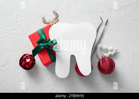Composition avec dent de papier, outils de dentiste et cadeau de Noël sur fond clair Banque D'Images