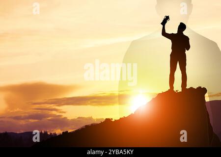 Vainqueur avec coupe trophée dans les montagnes au lever du soleil et silhouette de l'homme Banque D'Images