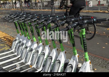 Trafic, mobilité, cyclistes et scooters électriques alignés de Lime en automne dans une rue de Berlin, Allemagne, Europe Banque D'Images