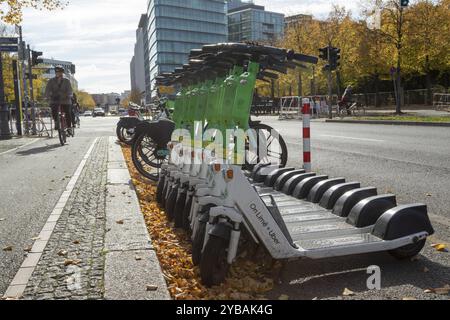 Trafic, mobilité, cyclistes et scooters électriques alignés de Lime en automne dans une rue de Berlin, Allemagne, Europe Banque D'Images