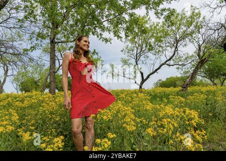 Un beau modèle brune profite d'un champ de fleurs jaunes un jour de printemps Banque D'Images