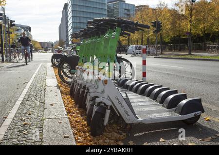 Trafic, mobilité, cyclistes et scooters électriques alignés de Lime en automne dans une rue de Berlin, Allemagne, Europe Banque D'Images