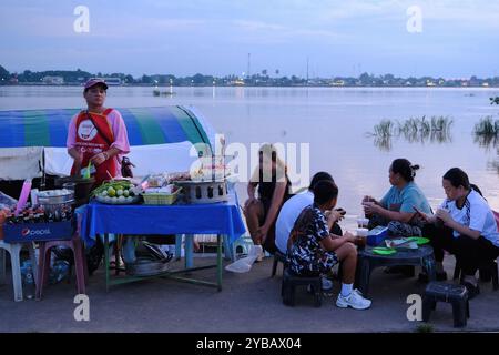 Une vendeuse de nourriture avec des clients mangeant à côté au marché nocturne du Mékong River. Vientiane, Laos Banque D'Images
