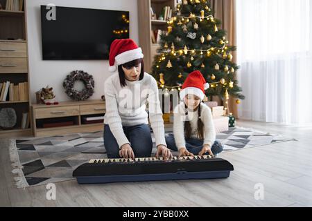 Mère et fille jouant des chansons de Noël au piano à la maison Banque D'Images