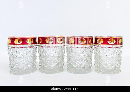 Une rangée de tasses en verre de cristal vintage avec des bords décorés, isolés sur un fond blanc. Banque D'Images