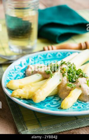 Plat fait maison avec des asperges blanches avec une sauce à la crème de noix de cajou, garni de persil haché. Banque D'Images