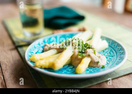 Plat fait maison avec des asperges blanches avec une sauce à la crème de noix de cajou, garni de persil haché. Banque D'Images