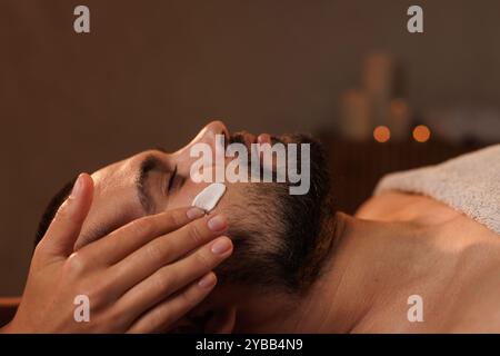 Cosméticienne appliquant la crème cosmétique de l'homme en spa. soins corporels Banque D'Images