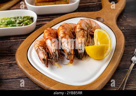 Crevettes rouges ou crevettes tigrées sur une assiette blanche avec des légumes verts et des tomates. Crevettes tigres Banque D'Images