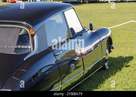 Black citroen ds est garé sur l'herbe, sa carrosserie polie reflétant le ciel et les nuages Banque D'Images