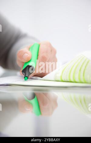 Close up of a woman holding a green surligneur sur un document papier Banque D'Images