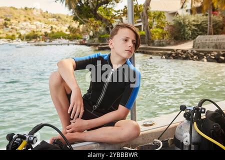 Adolescent en combinaison sur bateau avec équipement de plongée, Kingstown, Saint Vincent et les Grenadines Banque D'Images