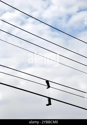 Photographie de bottes en caoutchouc suspendues sur des lignes électriques. Banque D'Images