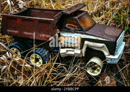 Photographie d'un vieux vieux vieux vieux vieux vieux métal rouillé vieilli camion à benne basculante Tonka dans un champ herbeux humide. Banque D'Images