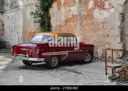 812 voiture classique américaine à toit doré Bordeaux rouge -Chevrolet de 1953- garée dans le terrain vacant d'un immeuble en ruines, Habana Vieja. La Havane-Cuba. Banque D'Images