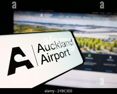 Téléphone portable avec le logo de la société Auckland International Airport Limited sur l'écran en face du site Web de l'entreprise. Focus à gauche de l'écran du téléphone. Banque D'Images