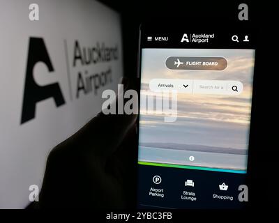 Personne tenant smartphone avec la page Web de la société Auckland International Airport Limited sur l'écran avec logo. Concentrez-vous sur le centre de l'écran du téléphone. Banque D'Images