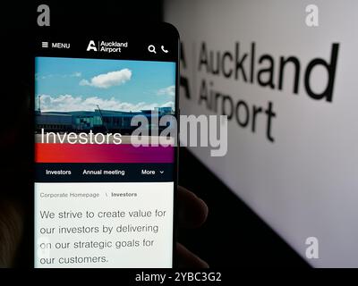 Personne tenant le téléphone portable avec la page Web de la société Auckland International Airport Limited sur l'écran avec logo. Concentrez-vous sur le centre de l'écran du téléphone. Banque D'Images