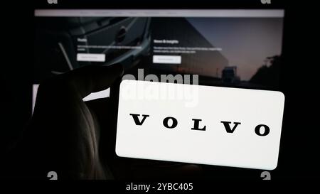 Personne tenant un smartphone avec le logo de la société automobile suédoise AB Volvo sur l'écran en face du site Web. Concentrez-vous sur l'affichage du téléphone. Banque D'Images