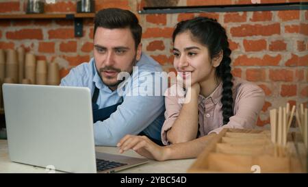 Gestionnaire de serveur souriant diversifié discutant de l'horaire de travail sur les employés de café d'ordinateur portable homme femme regardant l'écran d'ordinateur développant une nouvelle stratégie de travail Banque D'Images