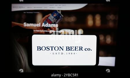 Personne tenant le téléphone portable avec le logo de la brasserie américaine Boston Beer Company sur l'écran en face de la page Web de l'entreprise. Concentrez-vous sur l'affichage du téléphone. Banque D'Images