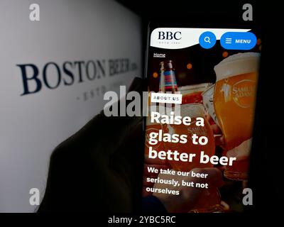 Personne tenant le téléphone portable avec la page Web de la brasserie américaine Boston Beer Company sur l'écran devant le logo. Concentrez-vous sur le centre de l'écran du téléphone. Banque D'Images